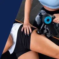 Eine Frau wird auf ihrem Oberschenkel mit einer Massagepistole massiert.