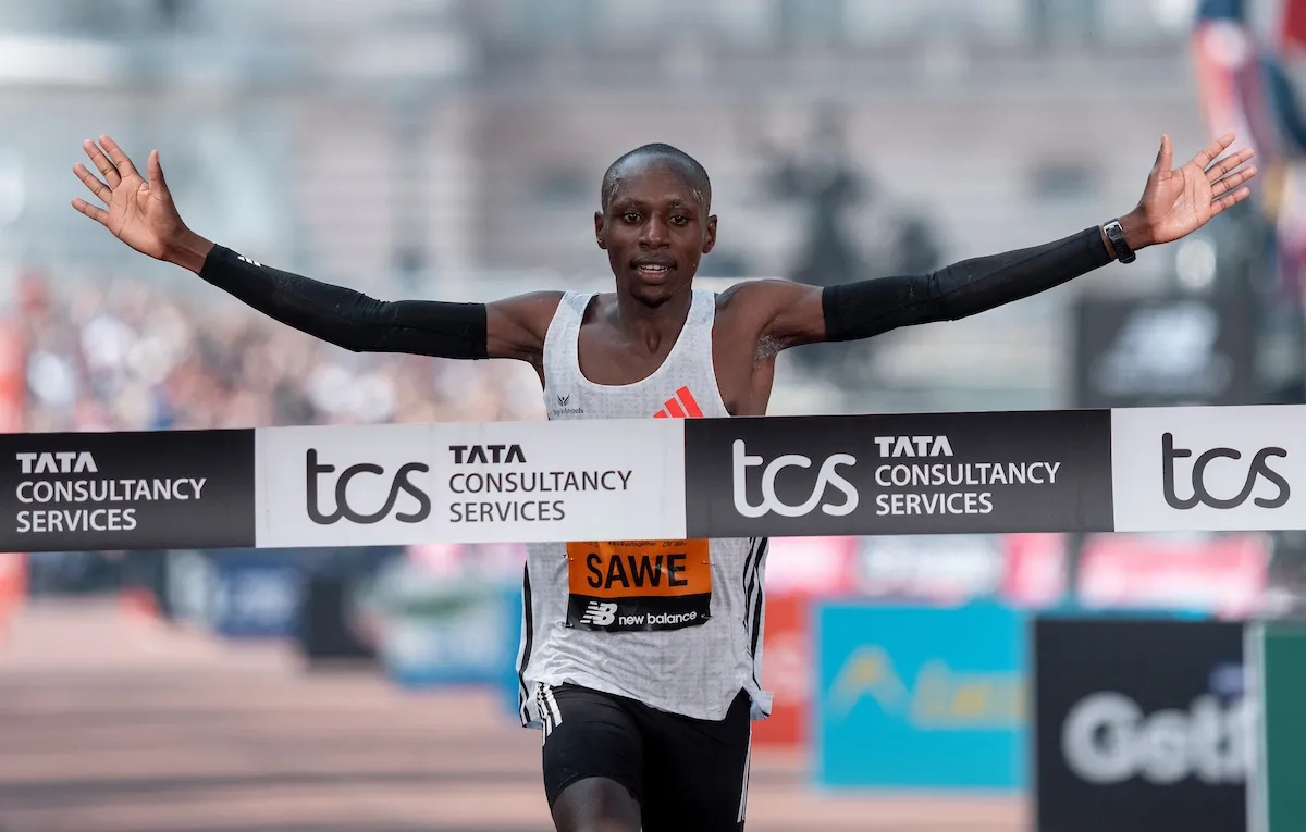 London Marathon 2025: Sabastian Sawe (KEN) reißt die Arme in die Höhe, als er die Ziellinie auf der Mall überquert und London Marathon gewinnt.